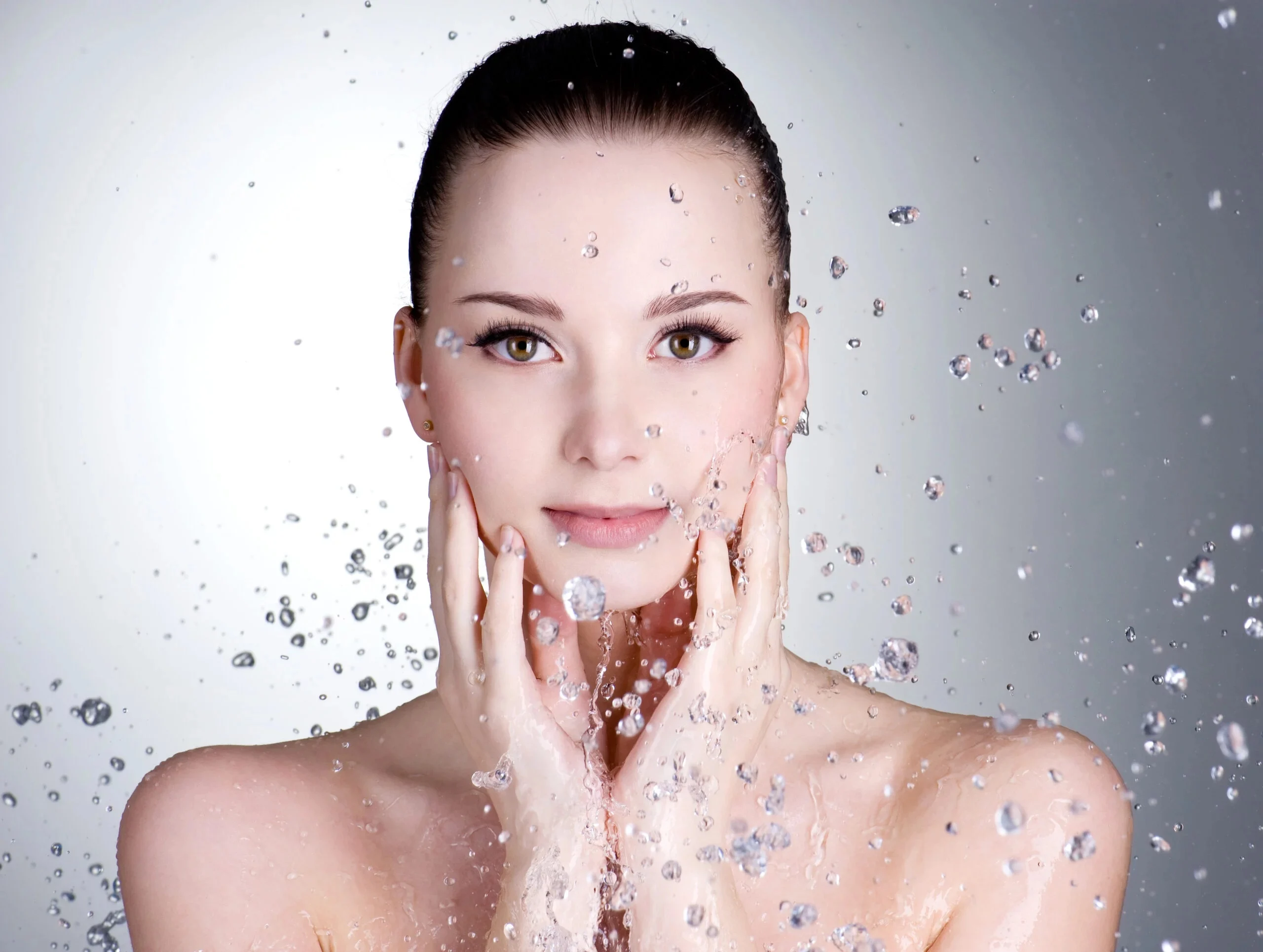 Femeie admir&acirc;nd stropii de apă care o &icirc;nconjoară &icirc;n timpul rutinei de &icirc;ngrijire Midwest Dermatology